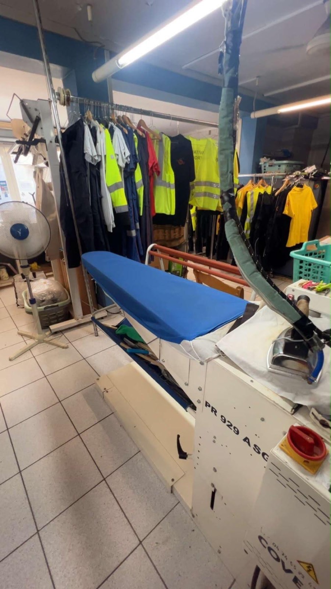 Atelier du pressing JUST IN WASH de Marignane : table à repasser et vêtements professionnels prêts à rendre